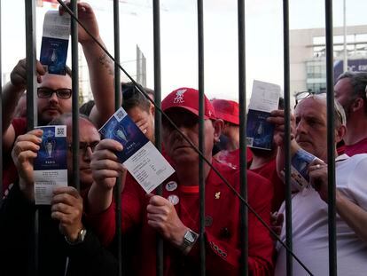 Liverpool fans show tickets and wait in front of the Stade de France prior the Champions League final soccer match between Liverpool and Real Madrid, in Saint Denis near Paris, Saturday, May 28, 2022. Police have deployed tear gas on supporters waiting in long lines to get into the Stade de France for the Champions League final between Liverpool and Real Madrid that was delayed by 37 minutes while security struggled to cope with the vast crowd and fans climbing over fences. (AP Photo/Christophe Ena)