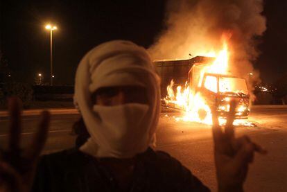 Un enmascarado hace el signo de la victoria ante un camión en llamas durante las protestas de ayer en el puerto omaní de Sohar.
