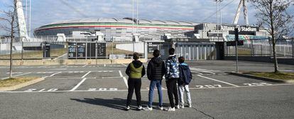 Cuatro jóvenes observan el Allianz Stadium tras la cancelación de varios partidos de la Serie A por el virus, en Turín, Italia.