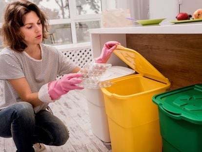 Una chica separa un envase plástico en la cocina de su casa.