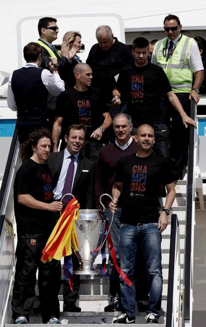 Puyol y Guardiola sujetan la Copa tras aterrizar en Barcelona.