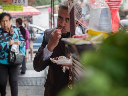 Un hombre come tacos en un puesto callejero en Ciudad de México, en 2021.
