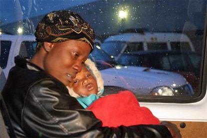 Una de las mujeres de la patera interceptada, sostiene a su bebé en el interior de una ambulancia.