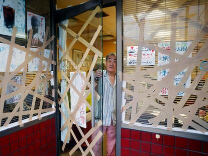 El dueño de una cafetería prepara los cristales de su establecimiento ante la llegada del tifón, en Uwajima, al suroeste de Japón.