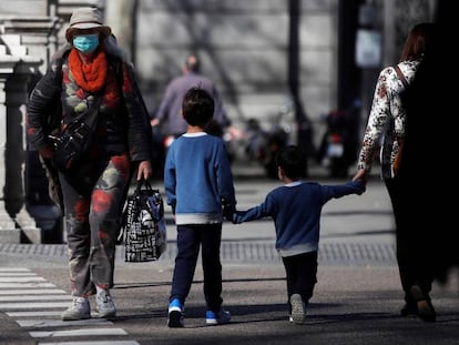 Un par de niños cruzan de la mano de su madre una calle en Madrid. 