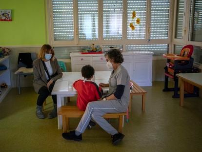 Dos trabajadoras acompañan a un menor mientras come en el centro de menores Juan Pablo II de Segovia.