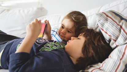 Uno niños miran dibujos animados en un dispositivo móvil en casa.