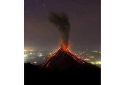 La ascensión al volcán Acatenango tiene premio: contemplar una erupción del volcán de Fuego. Verlo de noche es un espectáculo único: rocas incandescentes, ceniza, vapor de agua y gases y unos colores rojos que tiñen la noche. En la imagen, tomada en una noche sin luna, pueden verse además las estrellas y luces procedentes de la costa del Pacífico de Guatemala.