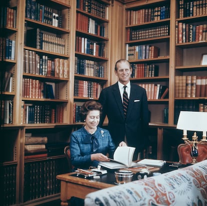 La Reina Isabel II y su marido, el príncipe Felipe, duque de Edimburgo, en su estudio del castillo de Balmoral en 1976.  La madera sin pintar, simplemente barnizada, es una constante en el mobiliario de Balmoral desde su construcción, como ejemplifica aquí la 'boiserie' de la biblioteca. Especial atención merece el estampado asiático de la tapicería del sofá. 