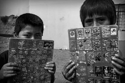 Dos niños muestran sus cuadernos escolares. Unos 100 niños trabajadores reciben clases de apoyo escolar gracias a la ONG ADEVI.
