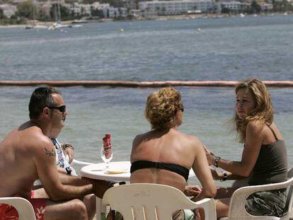 Tres turistas, en una terraza de la playa de Talamanca (Ibiza).