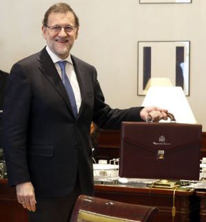 El presidente del Gobierno en funciones, Mariano Rajoy, posa con su maletín oficial tras formalizar su acta como diputado.