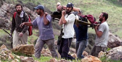 Colonos israel&iacute;es trasladan a un compa&ntilde;ero herido durante los choques con granjeros palestinos de la localidad de Madama, en Cisjordania. 