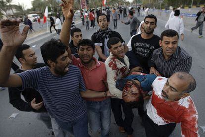 Manifestantes antigubernamentales trasladan a un compañero herido en las protestas de ayer en Manama.