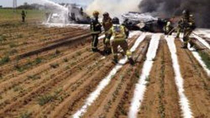 Bomberos extinguiendo el incendio provocado por el accidente del avión militar en los alrededores de Sevilla.