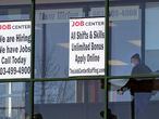 FILE - In this March 2, 2021, file photo, a woman, wearing a protective mask due to the coronavirus, walks past the signs of an employment agency, in Manchester, N.H. A new report finds that Latinas have left the workforce at rates higher than any other demographic and also have had some of the highest unemployment rates throughout the pandemic. (AP Photo/Charles Krupa, File)