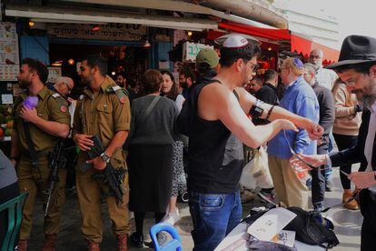 Soldiers pass in front of an ultra-Orthodox man on a Jerusalem street