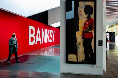 El cartel de la entrada a la exposición y 'Pissing Guard', una de las obras de Banksy que pueden verse en el Disseny Hub Barcelona.