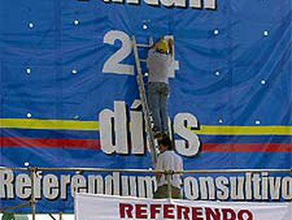 Un voluntario cambia el número de los días que quedan para la votación.