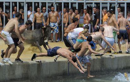 Los festeros se lanzan al agua para esquivar al toro en el puerto de Denia.