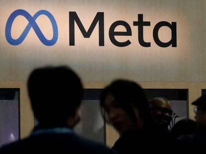 Dos personas frente al logo de Meta en una de sus sedes, San Francisco (EE UU).