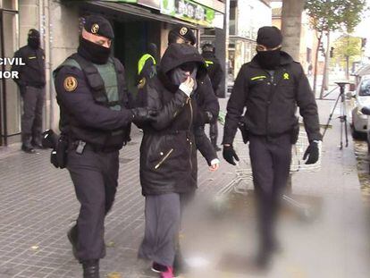 Dos agentes trasladan a una detenida por captar yihadistas, en Catalu&ntilde;a.