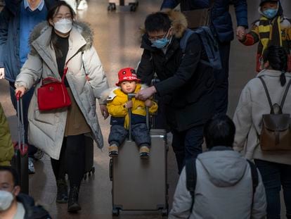 Un hombre empujaba una maleta con un niño agarrado al asa, en una estación de Pekín el pasado miércoles.