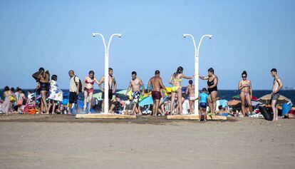 Un grupo de bañistas se ducha en una playa de Valencia