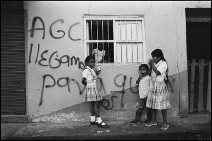 Niños de pie junto a un grafiti en una pared, traducido como: "AGC (Autodefensas de Colombia) hemos venido para quedarnos". Policarpa, Colombia, julio de 2009.
