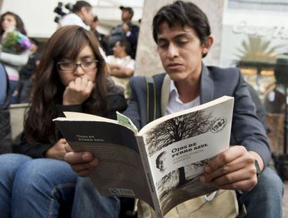 Dos jóvenes leen un libro de García Márquez frente a la funeraria donde están sus restos.
