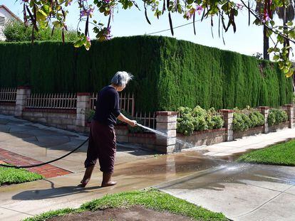 Una mujer lava con manguera la entrada de su casa en la ciudad de Monterey Park, al este de los Ángeles.