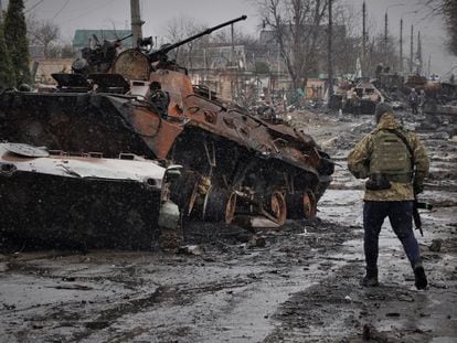 Un soldado ucranio observa un carro de combate ruso destrozado durante los primeros días de la invasión rusa, en Bucha (Ucrania).