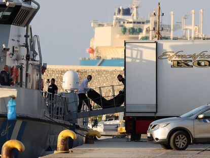 Dos hombres trasladan una bolsa con el cuerpo de uno de los migrantes fallecidos en el hundimiento de su barca en aguas griegas, en el puerto de Kalamata el pasado jueves.