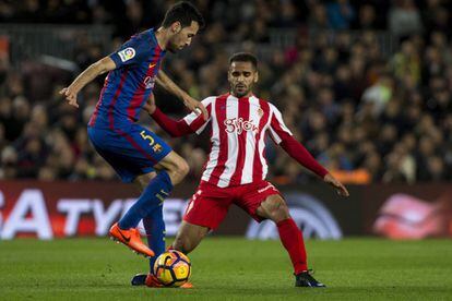 El centrocampista del Barcelona Sergio Busquets (izquierda) protege el balón ante el defensa brasileño del Sporting de Gijón Douglas Pereira (derecha).