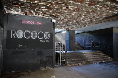 Un hombre sube las escaleras junto al cartel de una de las discotecas de los bajos, en evidente estado de abandono.