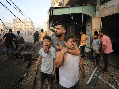 Dos niños palestinos heridos lloraban el pasado 25 de octubre mientras otros buscaban víctimas en el lugar de un ataque israelí contra un edificio residencial en Ciudad de Gaza.