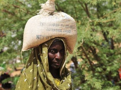 Una mujer acarrea un saco de comida distribuidos en una aldea de Burkina Faso. 