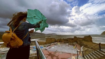 Una mujer trata de abrir su paraguas frente a la playa de Arrigunaga en Getxo (Bizkaia), el pasado 17 de agosto.