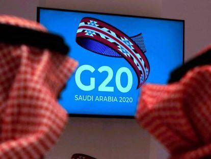 Dos funcionarios saudíes siguen en un televisor la reunión de ministros de Finanzas y gobernadores de los bancos centrales del G20 en Riad.