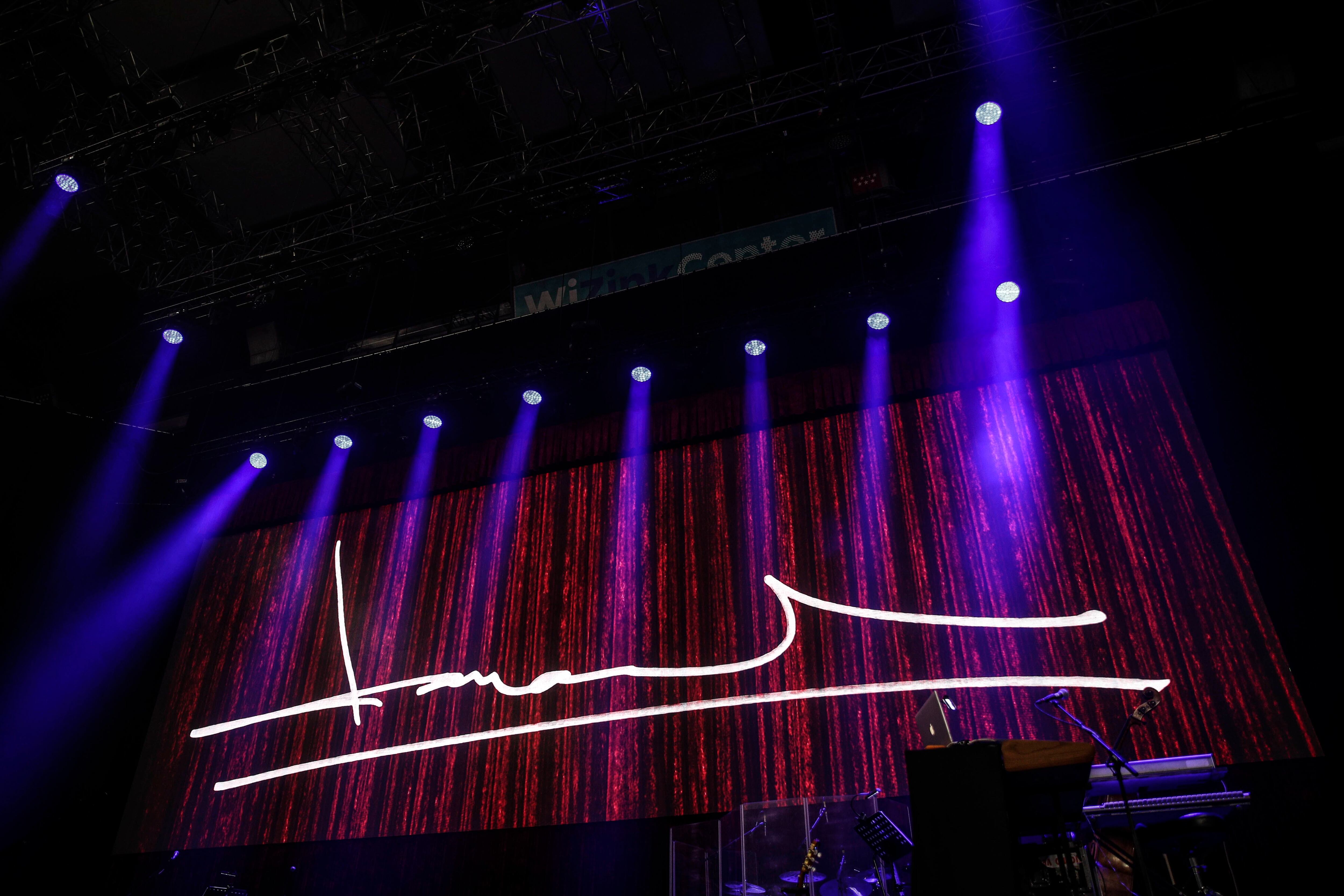 La firma del cantautor replicada con luces en el escenario.
