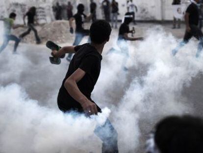 Un manifestante lanza un bote de gas a los antidisturbios durante una protesta en Manama.