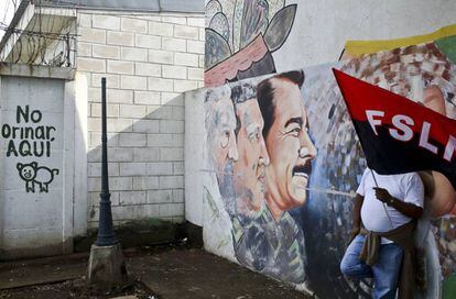 Un partidario de Ortega sostiene una bandera del partido sandinista FSLN apoyado en un mural el 26 de mayo.