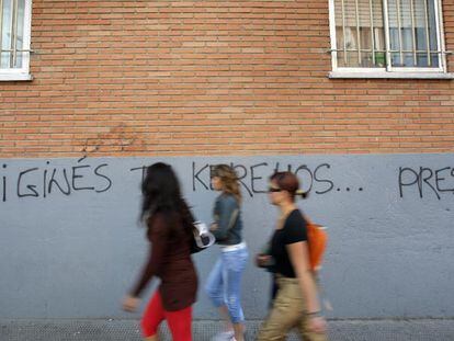 Tres mujeres pasan junto a una pared con una pintada contra el jefe de la Policía Local de Coslada.