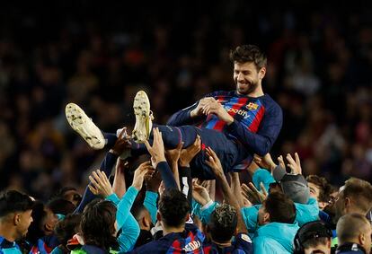 La plantilla del Barcelona mantea a un sonriente Gerard Piqué al final de su último partido.