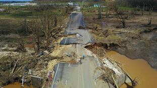 Un hombre se desplaza en bicicleta por una carretera destrozada por el huracán María en Puerto Rico, en septiembre de 2017.