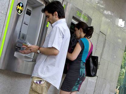 Dos clientes sacan dinero en sendos cajeros en la calle de Alcalá de Madrid.