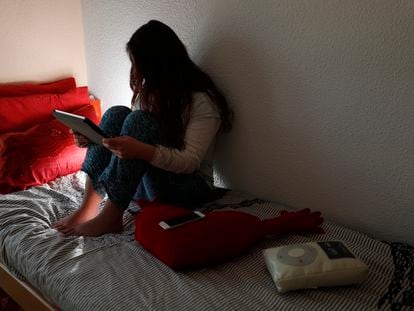 Una adolescente mirando uno de sus aparatos electrónicos.