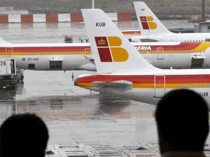 Dos pasajeros observan varios aviones de la compa&ntilde;ia Iberia en las pistas del aeropuerto de Barajas. EFE/Archivo