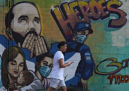 hombre camina frente a un mural que festeja la política de seguridad del presidente Nayib Bukele