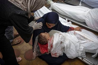 Una mujer sostenía a su hijo mientras extendía la mano para tocar el cuerpo de su marido, ambos muertos en un bombardeo del ejército israelí en la franja de Gaza, en el hospital de Jan Yunis, el martes.